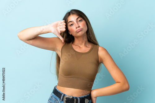 Young caucasian woman isolated on blue background showing thumb down with negative expression © luismolinero