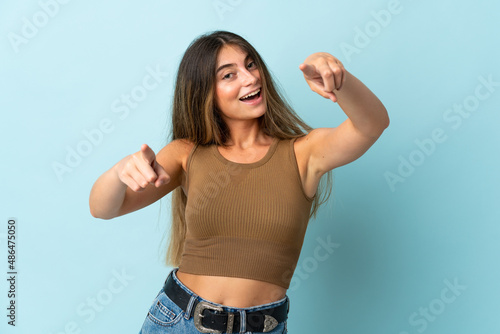 Young caucasian woman isolated on blue background pointing front with happy expression © luismolinero