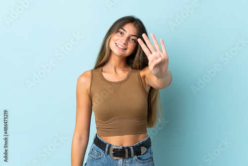 Young caucasian woman isolated on blue background happy and counting four with fingers