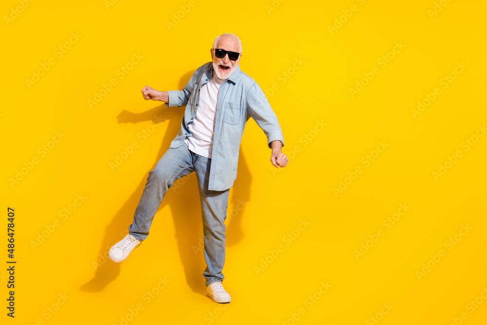 Full length body size view of attractive cheerful grey-haired man dancing moving having fun isolated over shine yellow color background Full length body size view of attractive cheerful grey-haired man dancing moving having fun isolated over shine yellow color background