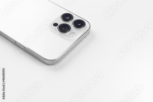 a white smartphone with three cameras lies on a  white background
