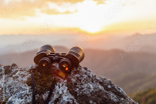 binoculars on top of rock mountain at sunset photo