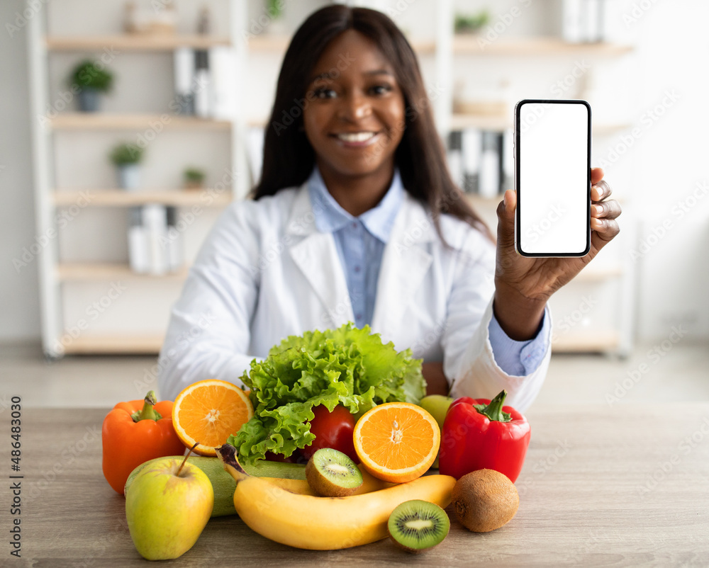 Modern dietary application. Happy african american nutritionist showing smartphone with blank screen, mockup Modern dietary application. Happy african american nutritionist showing smartphone with blank screen, mockup