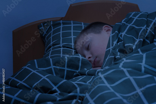 the boy sleeps in bed. the face of a child sleeping at night