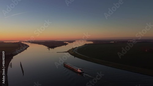 Ship sailing on the river Ijssel in the IJsseldelta during sunrset during a cold winter afternoon in Overijssel, Netherlands. photo