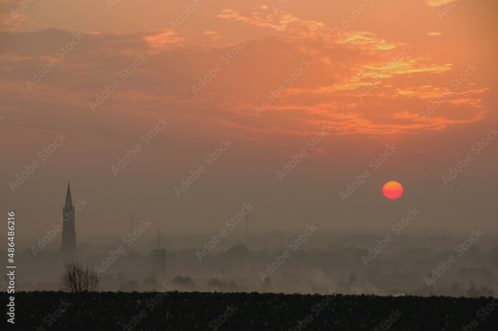 Zachód słońca nad spowitym w smogu miastem. - obrazy, fototapety, plakaty 