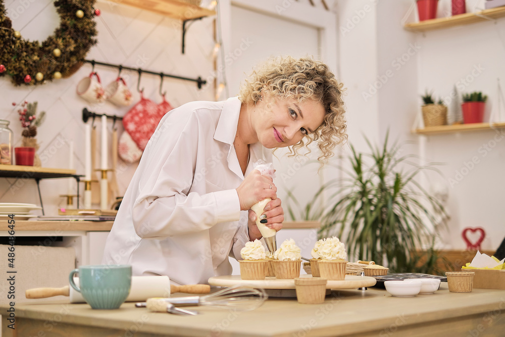 confectioner squeezes out a white cream in the form of roses flowers. process of decorating cupcakes with white whipped cream. Decorating a white cake with cream from the pastry bag. confectioner squeezes out a white cream in the form of roses flowers. process of decorating cupcakes with white whipped cream. Decorating a white cake with cream from the pastry bag.