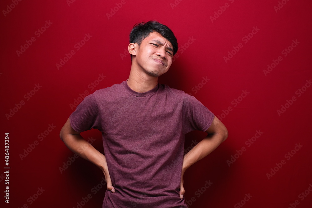 Asian man having stomachache on red background, health concept. Asian man having stomachache on red background, health concept.
