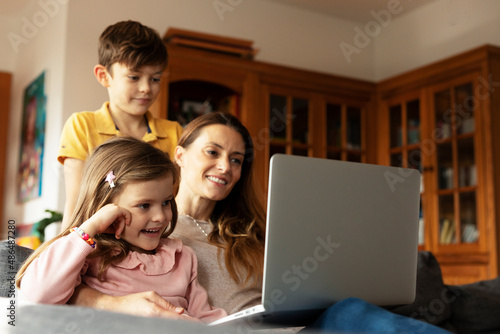 Cheerful little girl using laptop. Beautiful girl watching cartoon with mom.