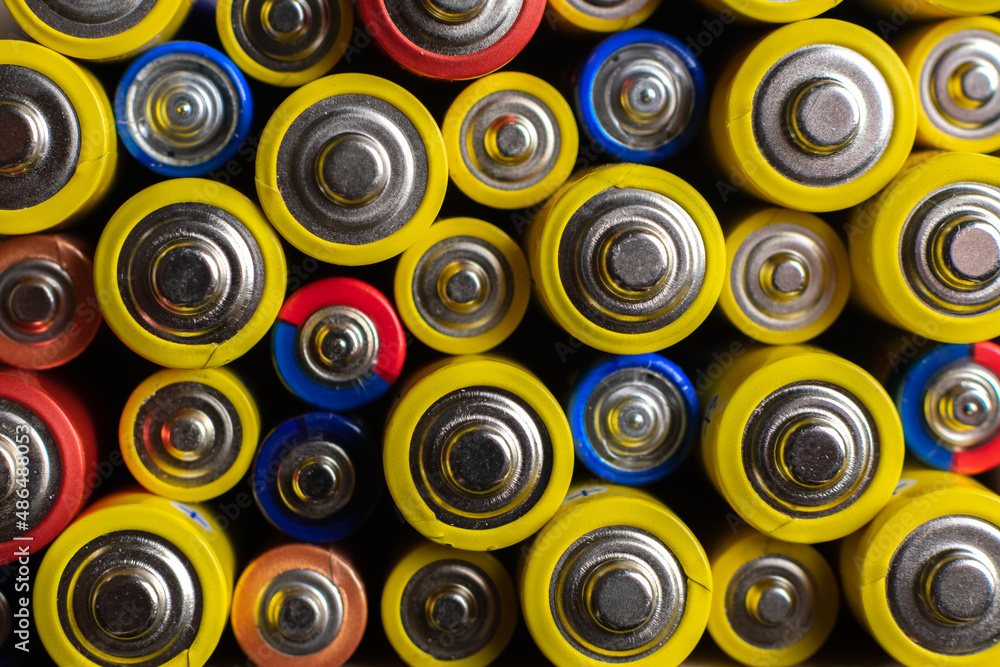 Background of colorful batteries. Close up top view on rows of selection of batteries. Many alcaline batteries. Macro. Background of colorful batteries. Close up top view on rows of selection of batteries. Many alcaline batteries. Macro.