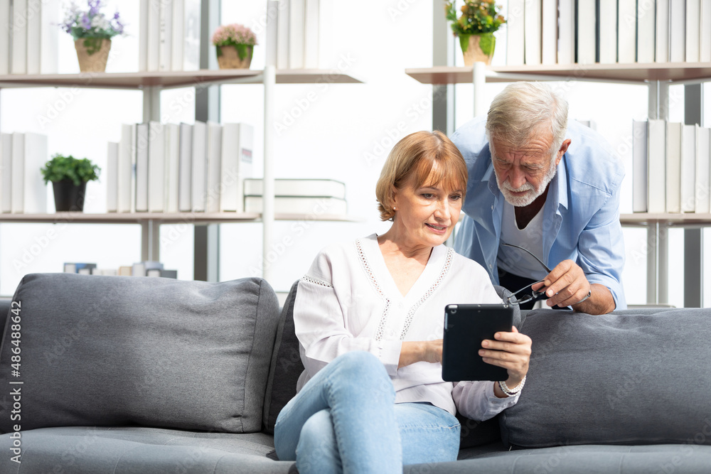 senior couple, elderly man and woman using tablet on sofa