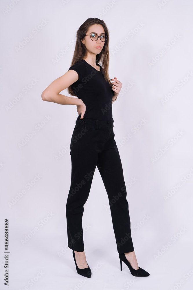 Young Female model in studio. high fashion portrait of young elegant woman. skinny black pants, black heels shoes. Young Female model in studio. high fashion portrait of young elegant woman. skinny black pants, black heels shoes.