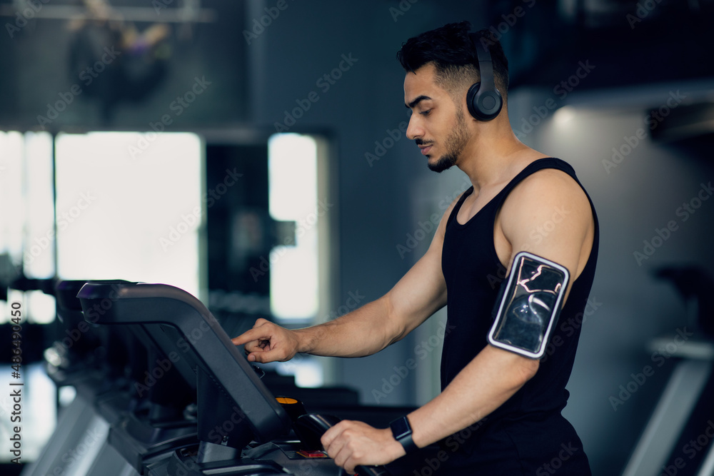 Gym Training. Young Middle Eastern Guy In Wireless Headphones Exercising On Treadmill