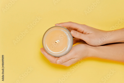 Female hands with scented candle and flowers. Aromatherapy and spa
