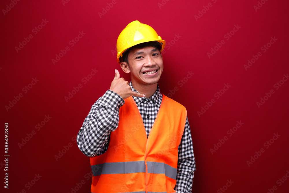 asian man on red background wearing contractor uniform and safety helmet with expression showing good work asian man on red background wearing contractor uniform and safety helmet with expression showing good work