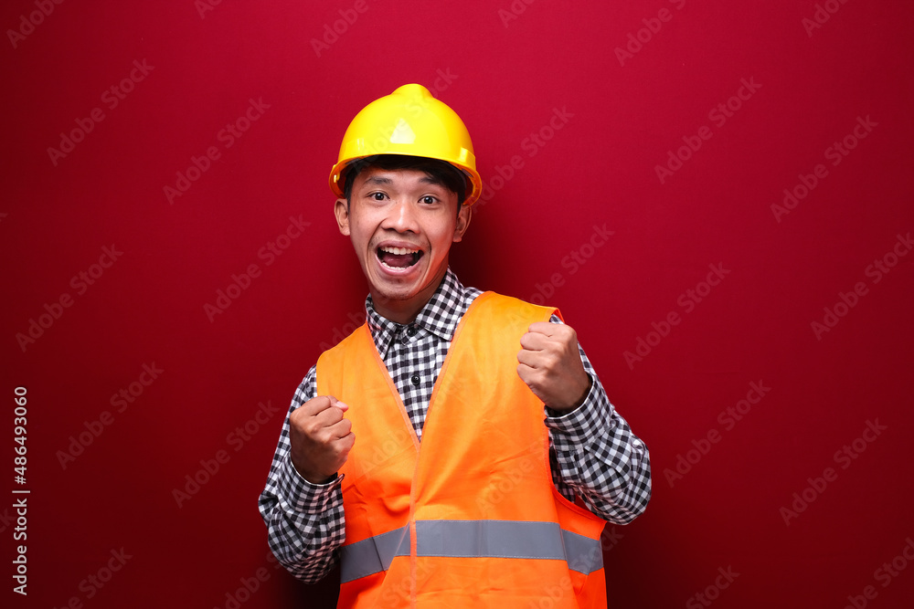 asian man on red background wearing contractor uniform and safety helmet with expression showing good work