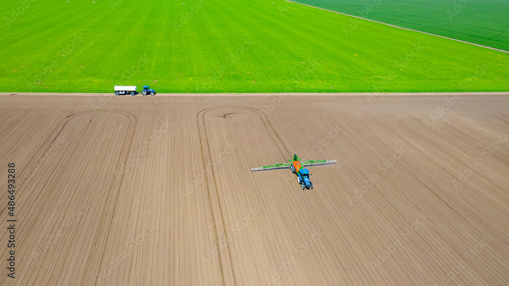 Aerial view on tractor as spraying field with sprayer, herbicide and pesticide