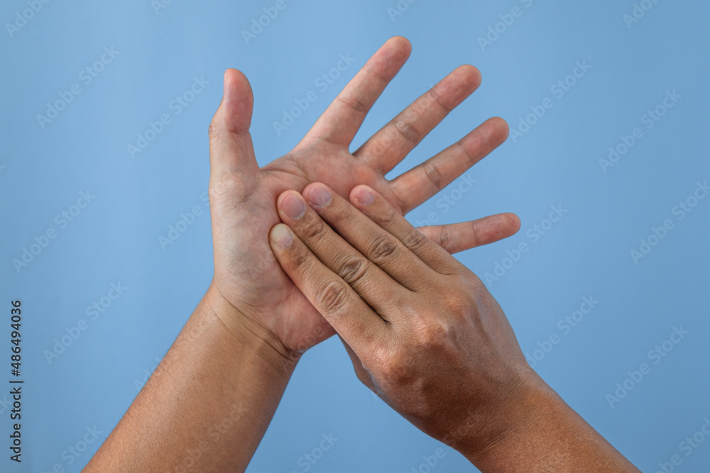 Office syndrome concept. Palm of hands are massaged after working by fingers. Close up shot isolate on blue background.