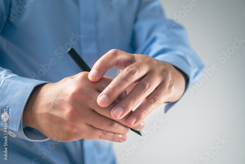 The man uses a pen until his fingers pain. Office syndrome concept. Medium close up shot with some copy space.
