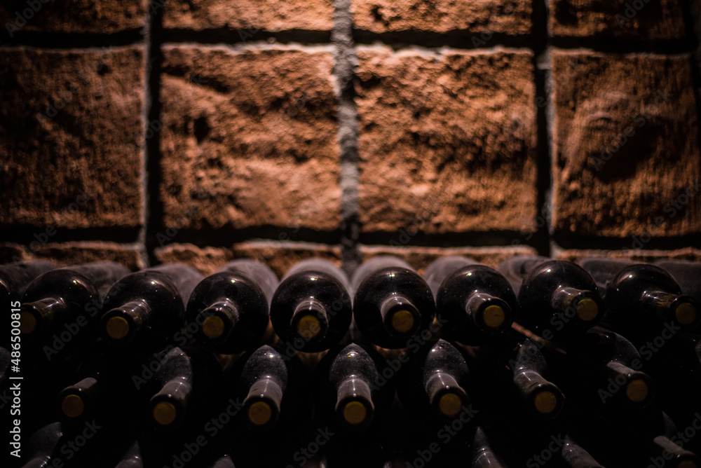 Obraz premium Old wine bottles in a old wine cellar stacked in rows. Dusty old green wine bottles whith corks. 