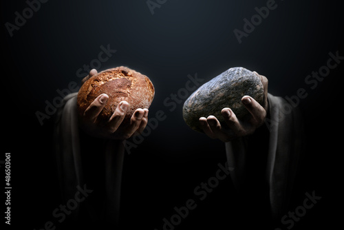 Hands of a man holding a stone and a bread. Religious biblical theme concept.
