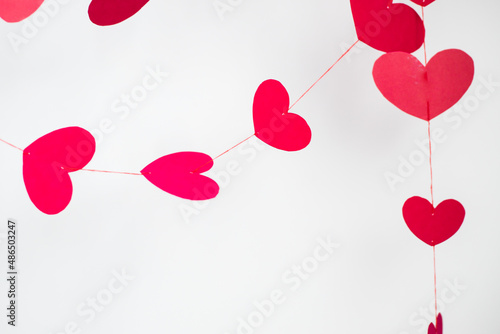 red and pink  hearts on red threads on a white background