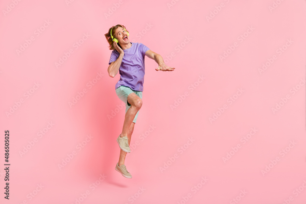 Full length body size view of attractive cheery crazy guy jumping listening hit dancing isolated over pink pastel color background