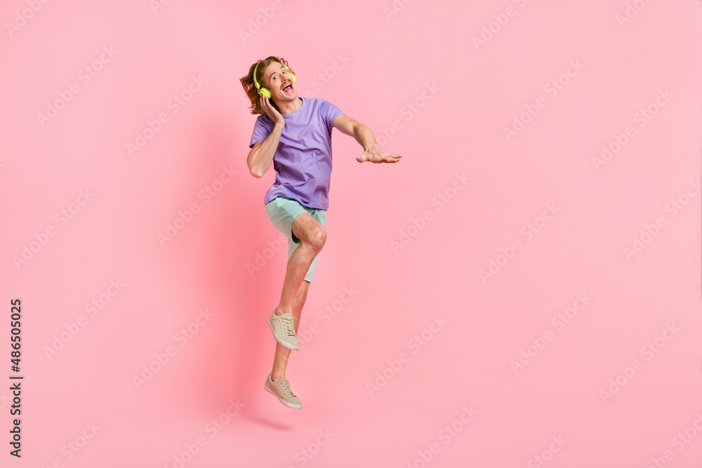 Full length body size view of attractive cheery crazy guy jumping listening hit dancing isolated over pink pastel color background Full length body size view of attractive cheery crazy guy jumping listening hit dancing isolated over pink pastel color background