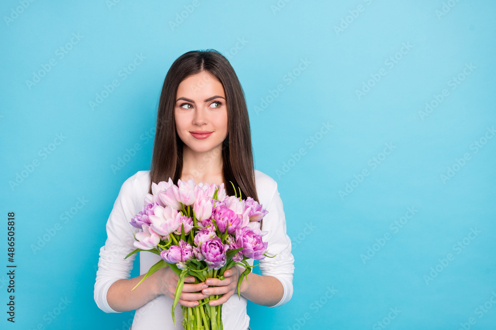 Portrait of attractive cheery minded girl holding flowers thinking copy blank space isolated over brigth blue color background