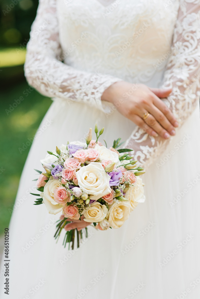 Beautiful wedding colorful bouquet in the hands of the bride. Wedding ring on the finger