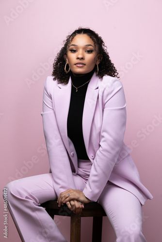 Editorial portrait of a confident young black successful business woman in a pink studio