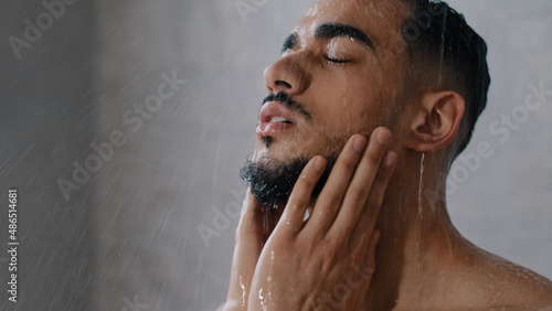 Принти на полотні Arab indian man bearded guy naked male washes head with shampoo washing hair face and beard in bathroom showering in at home in hotel after workout close up