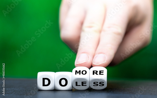 Hand turns dice and changes the expression "do less" to "do more".