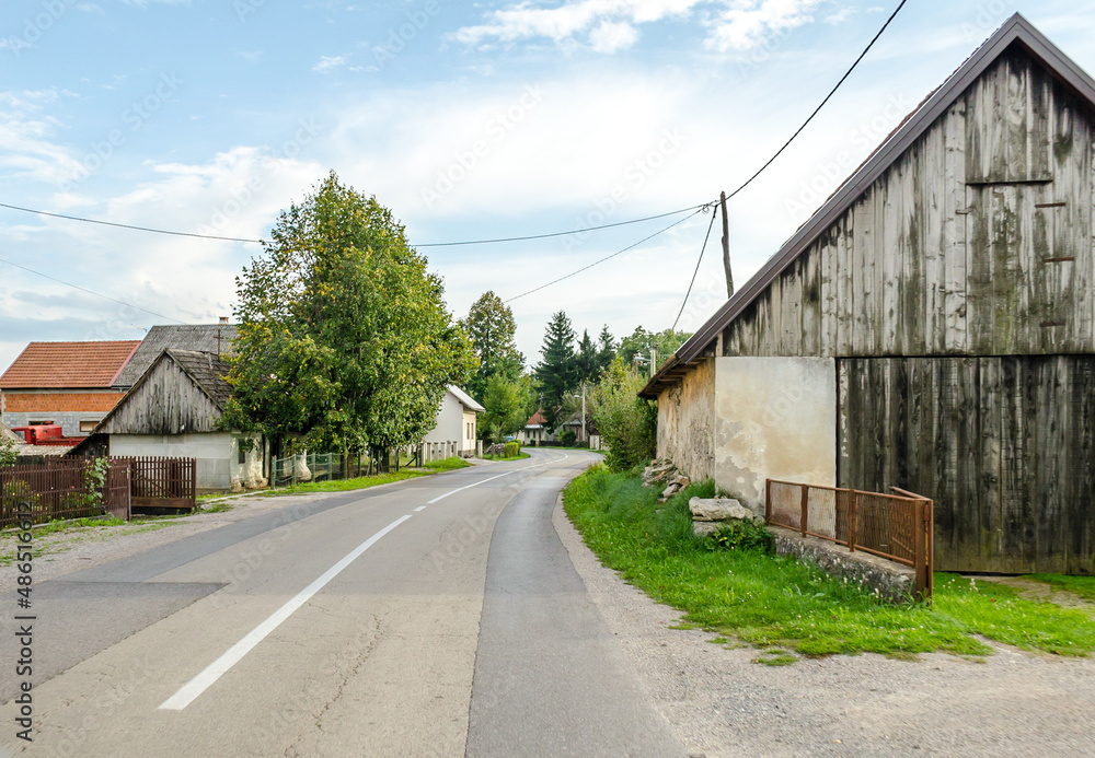 Driving on a Provincial Road through Villages in Croatian Countryside. Rural Scenery with Green Trees and Old Cottages on a Sunny Day. Driving on a Provincial Road through Villages in Croatian Countryside. Rural Scenery with Green Trees and Old Cottages on a Sunny Day.