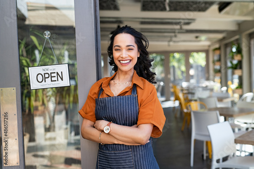 Successful small business owner standing at cafe entrance