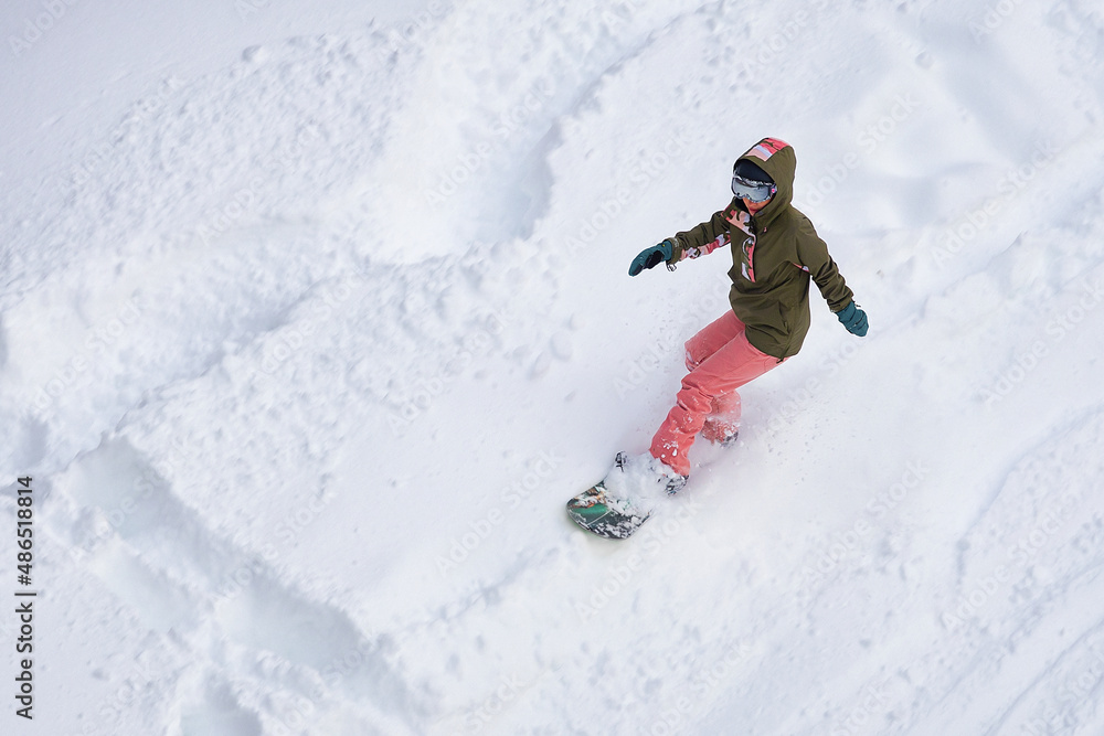 girl in helmet with glasses and tracksuit snowboarding down the mountain girl in helmet with glasses and tracksuit snowboarding down the mountain