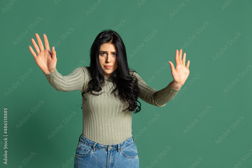 Portrait of young beautiful girl with long glossy dark hair isolated on green background. Concept of emotions, facial expression Portrait of young beautiful girl with long glossy dark hair isolated on green background. Concept of emotions, facial expression