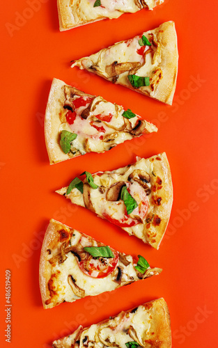 Assorted slices of pizza placed vertically on vibrant orange background