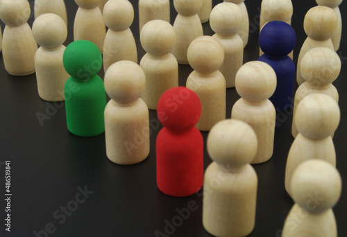 Crowd of wooden people figures, some figures colored close up. Individuality concept.
