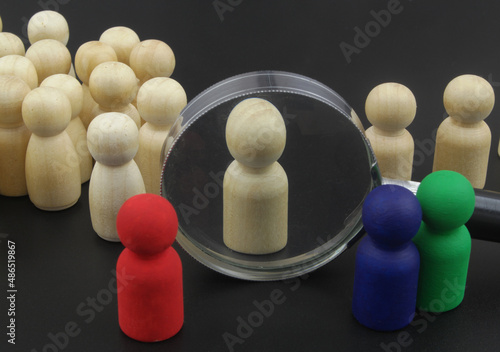 Colored figures choosing and check personnel. Wooden figures under magnifying close up. background. People identifying concept.