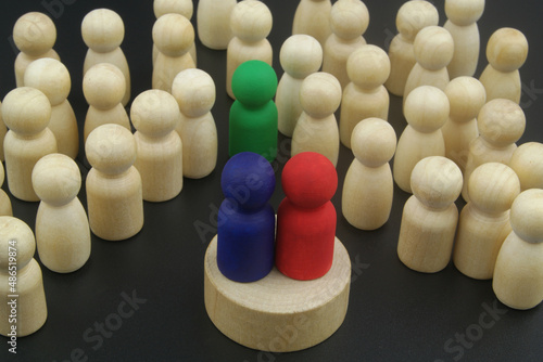 Political debates and election concept. Two different candidates or speakers - colored figures and many wooden figures with leader as people listening them.