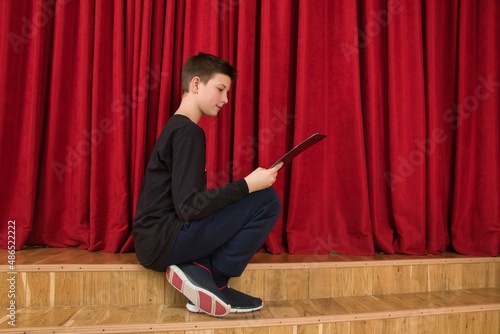 Backstage at the stage, a young actor is carefully studying his script