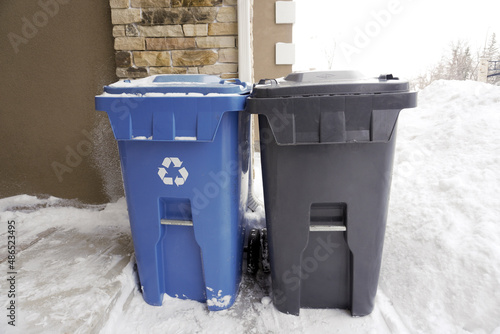 Blue and Black Garbage Trash Cans. Recycle and Regular Trash Collection.