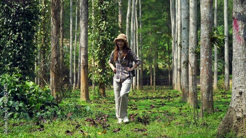 Young asian woman walking in forest with backpack. Walking to the camera.