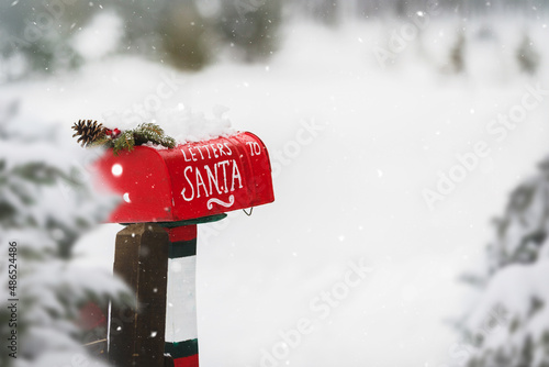 Red Christmas letter box  in a beautiful wintery snow covered landscape. Selective focus, copy space