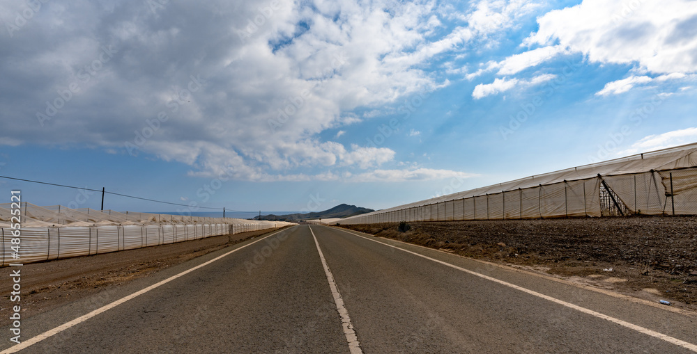 view of a highway passing through endless large greenhouses made of plastic in the waterless desert of southern Spain