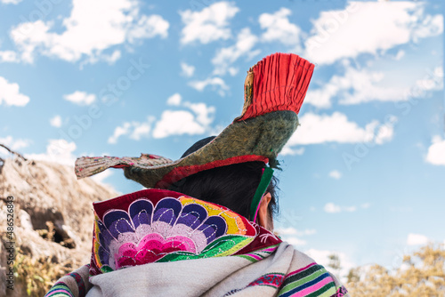 indigenous women walking dressed in typical dress made of alpaca fiber on a sunny day surrounded by clouds and a blue sky photo