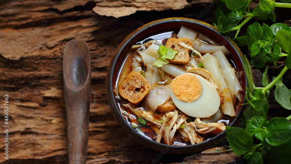 Chinese roll noodle soup, spoon, vegetable on wooden background