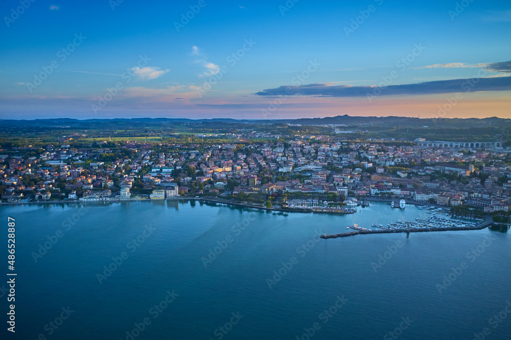 Aerial view. Beautiful Garda Lake with lighthouse (Lago di Garda). View from city of Desenzano del Garda, Italy, on sunny summer day. Natural background. Drone view of Desenzano del Garda. Aerial view