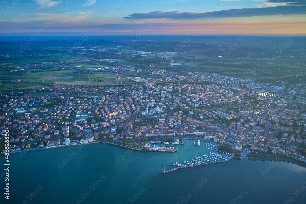 View from city of Desenzano del Garda, Italy, on sunny summer day. Natural background. Drone view of Desenzano del Garda. Aerial view. Beautiful Garda Lake with lighthouse (Lago di Garda).